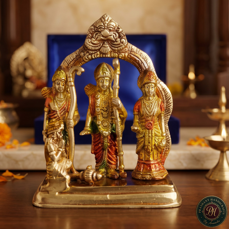 A decorative brass Hindu deity statue set featuring Lord Hanuman, Goddess Lakshmi, and Ganesha under an ornate arch, displayed on a wooden altar with a blue background box.