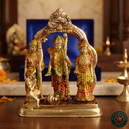 A decorative brass Hindu deity statue set featuring Lord Hanuman, Goddess Lakshmi, and Ganesha under an ornate arch, displayed on a wooden altar with a blue background box.